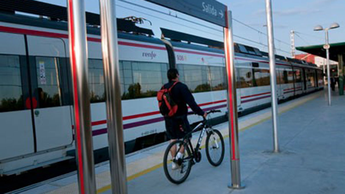 Un viajero de Renfe llevando su bici por el andén de la estación.