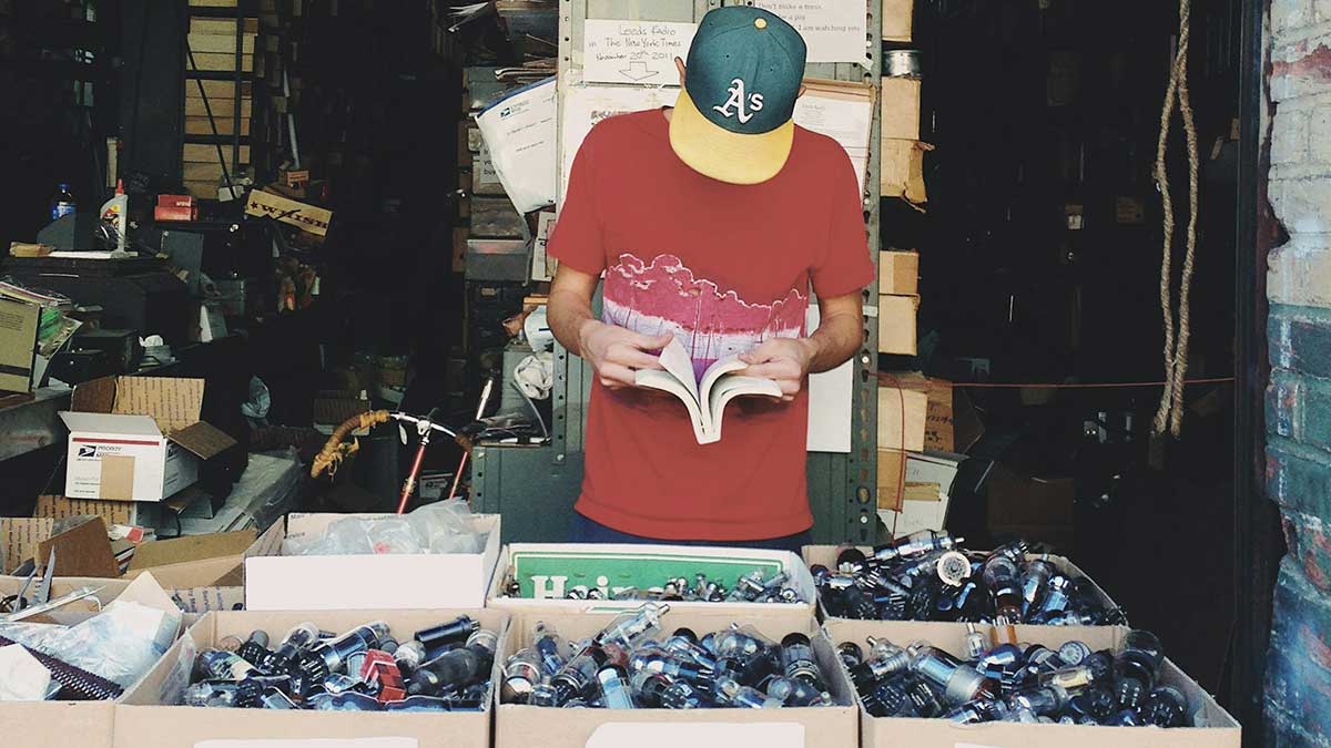 Una persona leyendo un libro de segunda mano en un mercadillo.