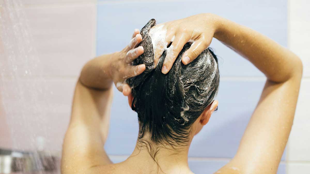 Una mujer lavando su pelo en la ducha.