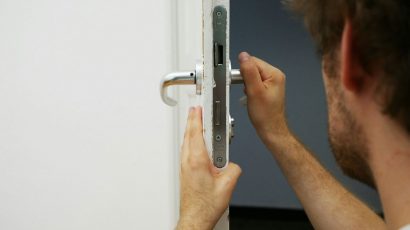 Una persona mirando la cerradura de la puerta de casa.