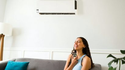 Una mujer en el salón de casa con el aire acondicionado encendido.