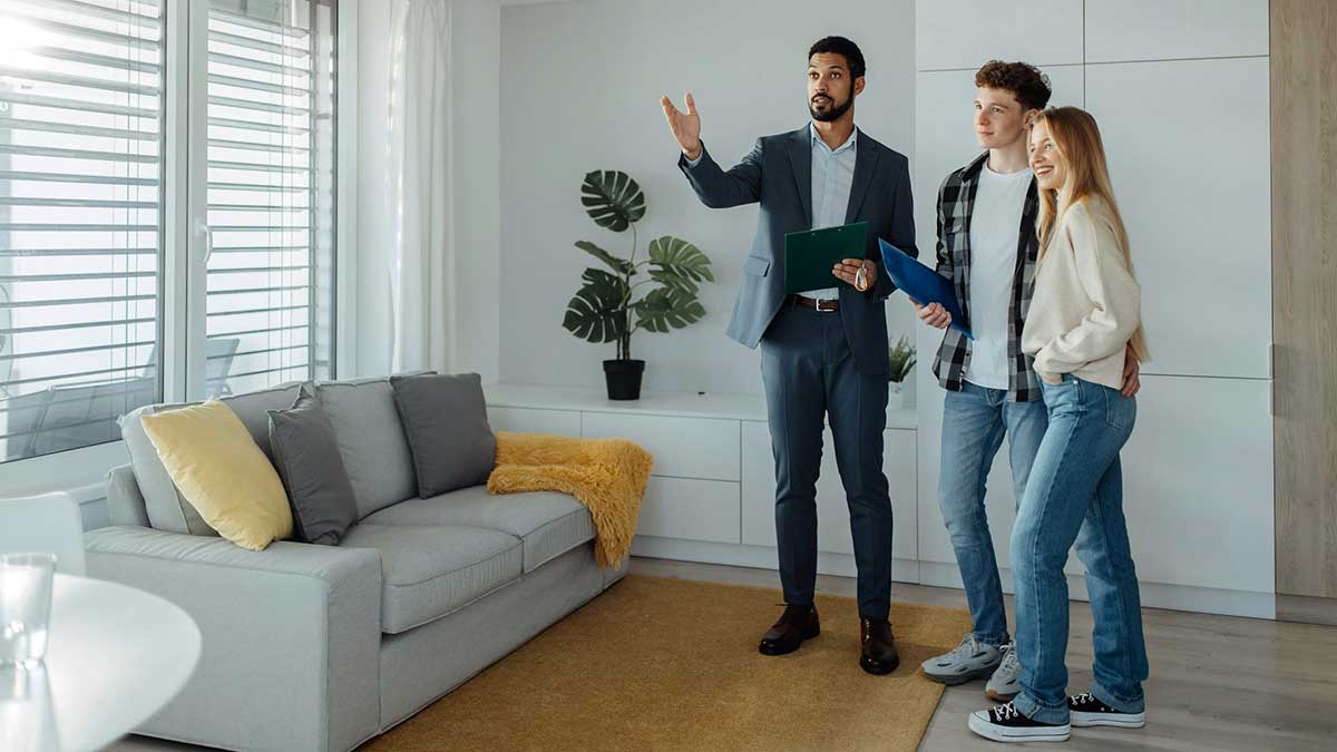 Unos jóvenes ven una vivienda para comprar con un agente inmobiliario.