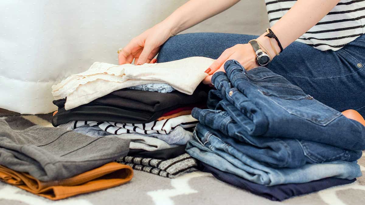 Una mujer doblando la ropa planchada.