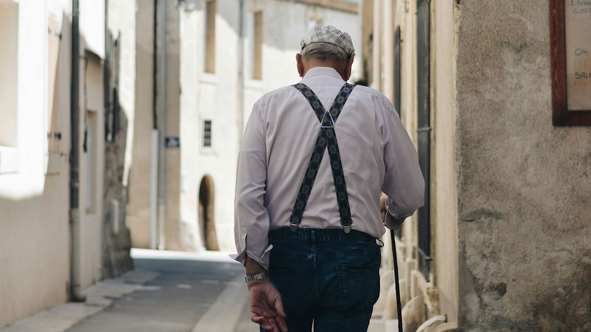 Un hombre jubilado paseando por las calles de un pueblo.