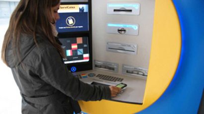 Una mujer sacando dinero de un cajero automático con el móvil.