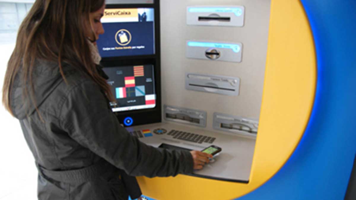 Una mujer sacando dinero de un cajero automático con el móvil.