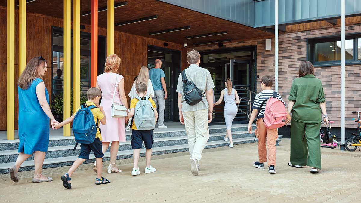 Padres acompañando a sus hijos a la entrada de un colegio.