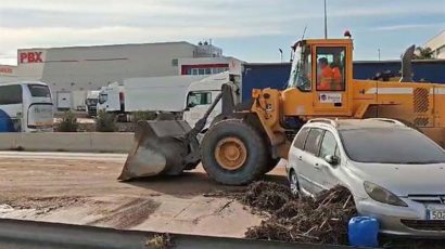 Excavadora limpiando barro de una carretera en un polígono de Valencia.