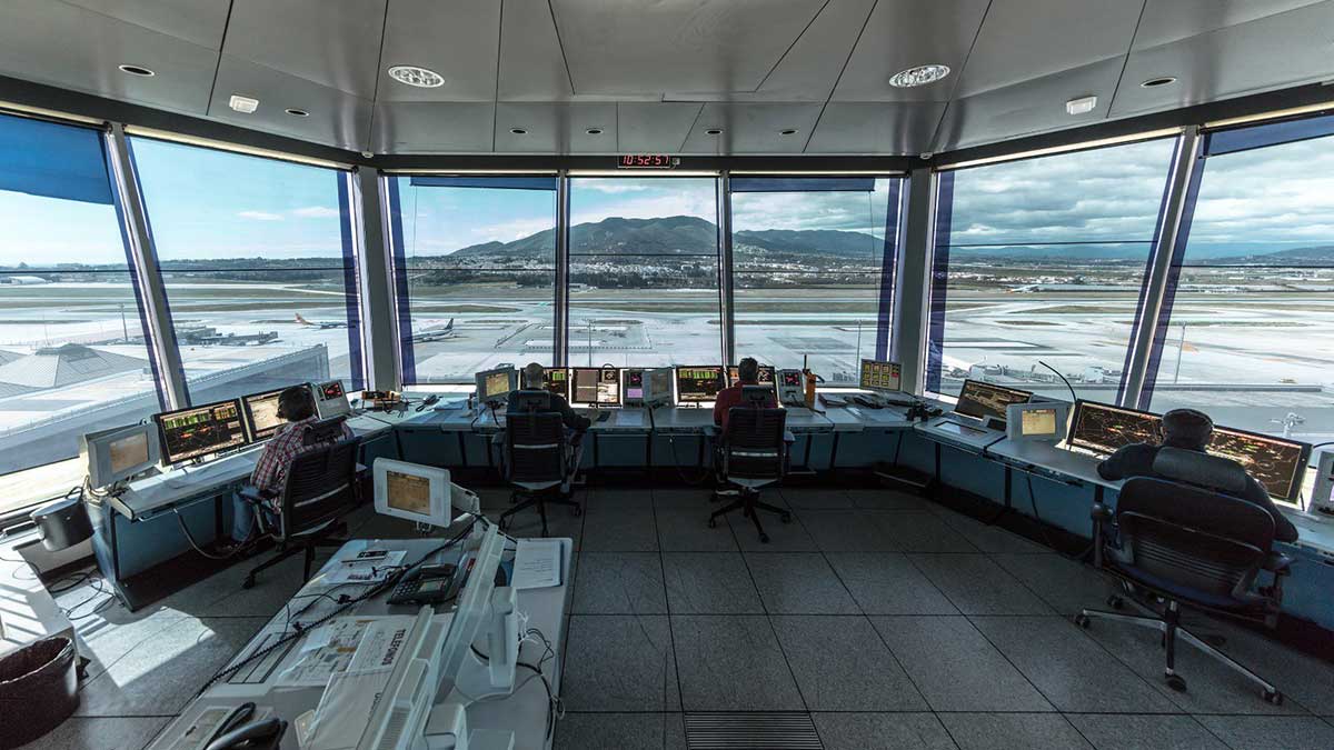 Controladores aéreos desempeñando su trabajo en una torre de control en un aeropuerto.