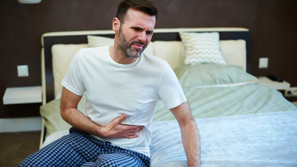 Un hombre con dolor de estómago, síntoma del norovirus.