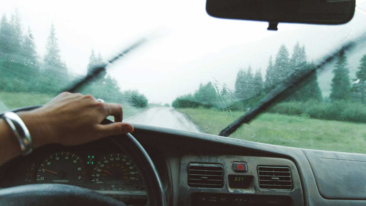 Una persona conduciendo con lluvia y usando el limpiaparabrisas.