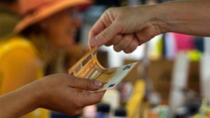 Una persona pagando en efectivo en un pequeño comercio.